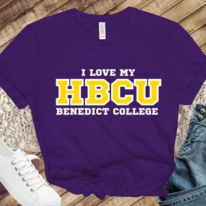 May include: Purple t-shirt with white text that reads "I love my HBCU Benedict College" in yellow block letters.
