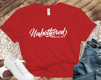 May include: Red t-shirt with white text that says "Unbothered Mood 24/7".