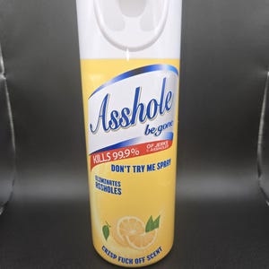 K&ouml;nnte beinhalten: Eine wei&szlig;-gelbe Spr&uuml;hflasche mit dem Text "Asshole be gone" und "Kills 99.9% of jerks & assholes". Auf der Flasche steht auch "Don't try me spray" und "Eliminates assholes". Auf der Unterseite der Flasche steht "Crisp fuck off scent".