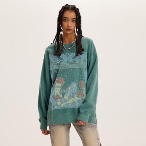 Op de afbeelding: Teal groene sweatshirt met een grafische print van paddenstoelen en figuren. Het ontwerp bevat blauwe en bruine tinten, met een vintage esthetiek. De top met lange mouwen heeft een ronde hals en een relaxte pasvorm.