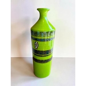 May include: A tall, cylindrical lime green ceramic vase with a narrow neck and flared rim. The body features two horizontal bands of dark brown, textured geometric patterns and a small, circular sticker with the Italian flag colors.