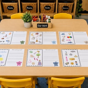 Op de afbeelding: Zes rechthoekige educatieve werkbladen met geschulpte zwarte randen op een lichthouten tafel. Elk blad bevat kleurrijke illustraties van objecten en lege regels om te schrijven, met specifieke lettercombinaties zoals ou, oo, igh, ow, ee en ay.
