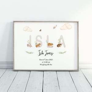 May include: A framed print featuring the name "Isla" in large letters, with watercolor illustrations of woodland creatures. The print includes the baby's birth date, time, and weight: 6lb 9oz. The design incorporates soft colors and a whimsical aesthetic.