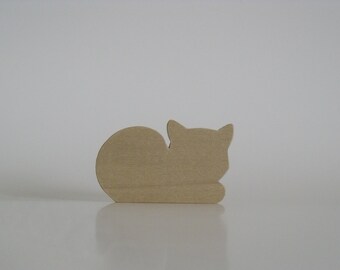 May include: A wooden cutout of a cat lying down. The cutout is a light brown color and has a simple, stylized design.