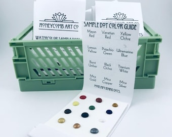 May include: A green plastic basket holds two white cards with the text "HONEYCOMB ART CO" and "WATERCOLOR SAMPLE DOTS". A sample dot color guide displays various colored dots and color names, including "Mayan Red" and "Venetian Red".