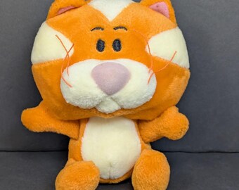 Op de afbeelding: Een oranje en witte pluche kat met een roze neus, zwarte ogen en oranje snorharen. De kat heeft een witte vlek op het voorhoofd en de borst, en roze oren. Een zacht en knuffelbaar speelgoed voor kinderen.