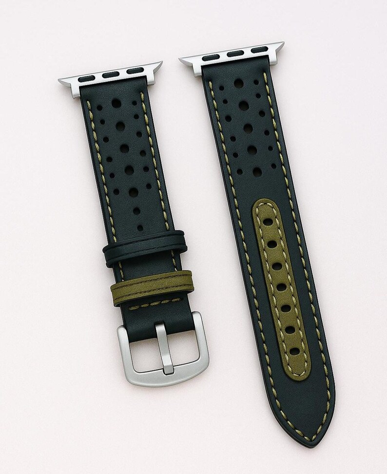 May include: Black leather watch band with perforated detailing and olive green accents. The band features a silver buckle and is shown with a silver smartwatch. The text "No:2" is visible.