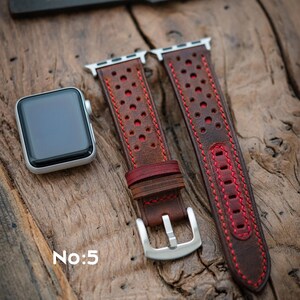 May include: A brown leather watch strap with red stitching and a perforated pattern. A silver Apple Watch sits beside the strap on a wooden surface. The text "No:5" is visible in the lower left corner.