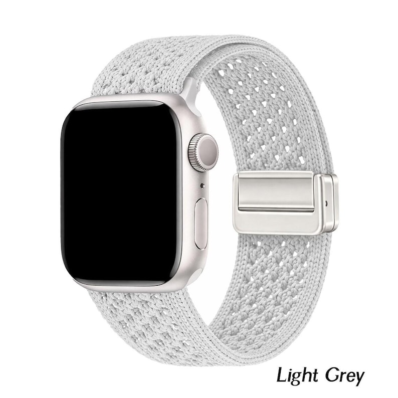 May include: A light grey smartwatch with a rectangular black screen and a silver metallic casing. The watch features a textured, woven fabric band with a matching silver-toned magnetic clasp mechanism. The text Light Grey is visible.