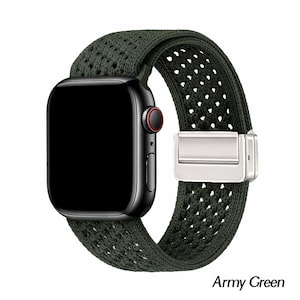 May include: A black smartwatch with a dark screen and a red ring on the side button, featuring an army green woven nylon watch band with a silver-toned metal magnetic clasp. The band has a textured, perforated pattern throughout its length.