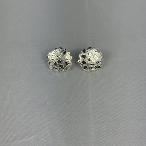May include: A pair of silver-toned stud earrings. Each earring has a textured, rounded design with dark accents, creating a unique, organic appearance. The earrings are displayed against a neutral gray background.
