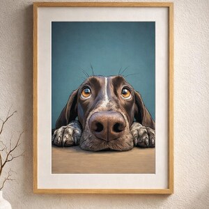 Puede incluir: Impresión enmarcada que presenta un primer plano de la cara de un perro. El perro tiene pelaje marrón y blanco, con ojos marrones grandes y expresivos y una nariz prominente. La obra de arte está sobre un fondo verde azulado y enmarcada en madera clara.