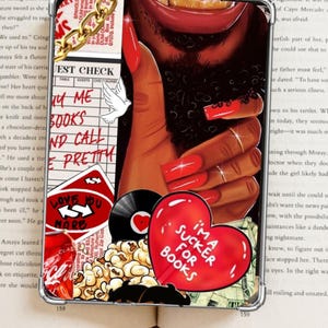Op de afbeelding: Transparante telefoonhoes met een collage van afbeeldingen. Een hand met lange rode nagels is prominent aanwezig, samen met een rood hart met de tekst "I'm a sucker for books". Andere elementen zijn een plaat, popcorn en tekst.