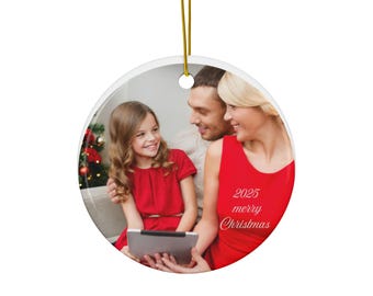 Peut inclure: Ornement de Noël rond avec un portrait de famille. L'image présente une famille souriante de trois personnes, avec le texte "2025 merry Christmas" en rouge. L'ornement a une ficelle dorée pour l'accrocher.