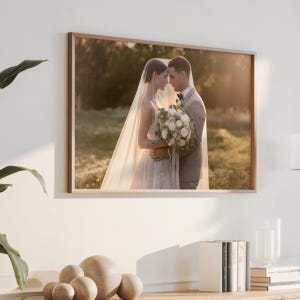 Personalized wedding photo print in landscape orientation, framed in wood above a living-room console — a bride and groom at golden hour made into custom canvas wall art.