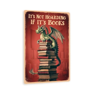 May include: A green dragon sits atop a large stack of books in a red room with bookshelves. The text on the sign reads "It's not hoarding if it's books."