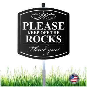 May include: Black and white sign that reads "PLEASE KEEP OFF THE ROCKS" with "Thank you!" below. The sign has a decorative top and is mounted on a metal pole. The bottom of the image shows green grass.