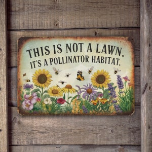 May include: A metal sign with a rustic background featuring a colorful garden scene with sunflowers, butterflies, and bees. The sign reads "This is not a lawn. It's a pollinator habitat."