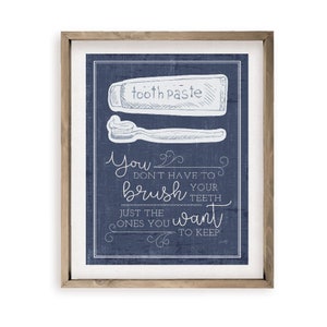 May include: A framed blue and white print with a toothbrush and toothpaste illustration and the text "You don't have to brush your teeth, just the ones you want to keep."