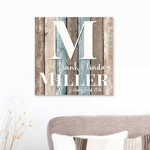 May include: A rustic wooden sign with a white letter "M" and the text "Frank & Linda Miller Established 2016". The sign has a distressed wood background with brown and blue tones.