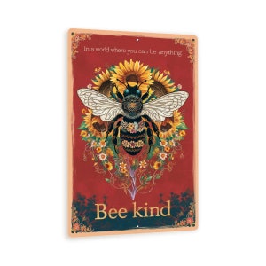 May include: A red metal sign with a bee surrounded by sunflowers and the text "In a world where you can be anything, Bee kind."