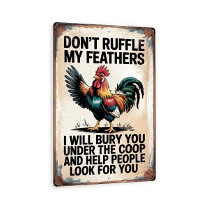 May include: Rectangular metal sign with a distressed finish. The sign features a colorful rooster illustration with text that reads "DON'T RUFFLE MY FEATHERS. I WILL BURY YOU UNDER THE COOP AND HELP PEOPLE LOOK FOR YOU."
