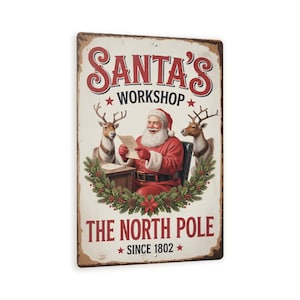 May include: A rectangular metal sign with a vintage design. The sign features Santa Claus reading a list, surrounded by reindeer and a wreath. The text reads "SANTA'S WORKSHOP" and "THE NORTH POLE SINCE 1802". The sign has a distressed, aged appearance.