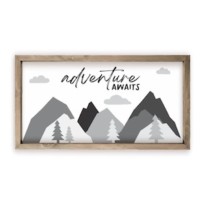 May include: A framed print with a black and white mountain landscape and the text "adventure awaits".