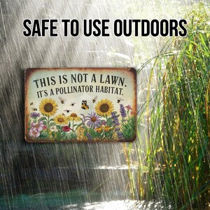 May include: A metal sign with a rustic background featuring a colorful illustration of a garden with flowers, butterflies, and bees. The sign reads "This is not a lawn. It's a pollinator habitat."