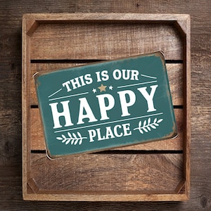 May include: Teal metal sign with white text that reads "This is our Happy Place" with a gold star and leafy sprigs.