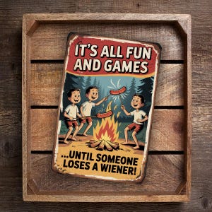 May include: A rectangular metal sign with the text "IT'S ALL FUN AND GAMES" in red and white. The sign features a cartoon illustration of three children roasting hot dogs over a campfire, with the text "...UNTIL SOMEONE LOSES A WIENER!"