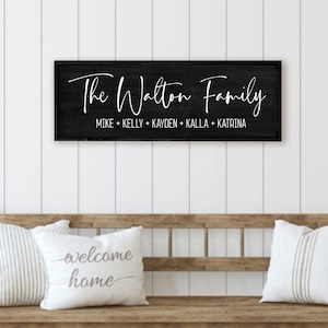 Personalized wooden name sign for your home. Custom wooden name sign perfect for farmhouse wood decor. Ideal as a personalized family frame, family name sign, and personalized family home decor. A distressed black wood background and a black frame.