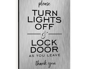 May include: A brushed silver sign with black text that reads "Please turn lights off & lock door as you leave thank you".