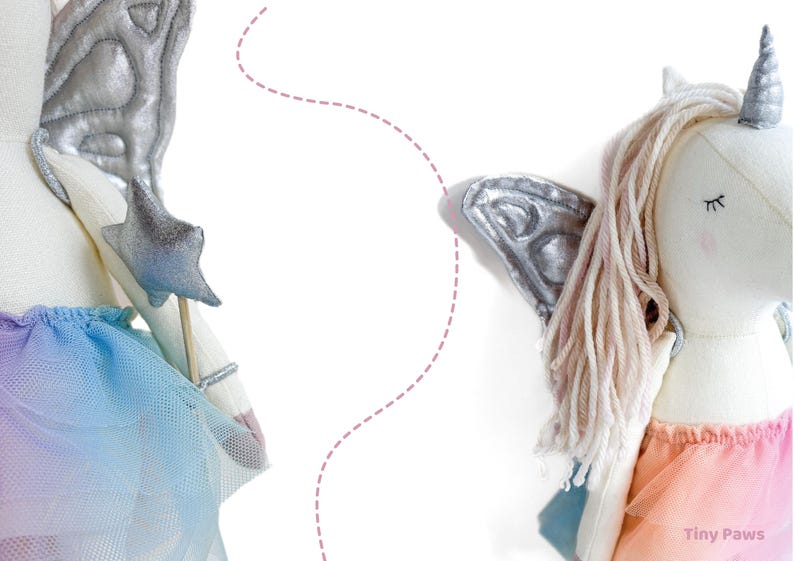 K&ouml;nnte beinhalten: Zwei Pl&uuml;sch-Einhorn-Puppen mit silbernen Fl&uuml;geln und einem sternf&ouml;rmigen Zauberstab. Eine Puppe hat einen Regenbogen-T&uuml;llrock, die andere einen rosa-orangenen Rock. Beide haben geschlossene Augen und ein silbernes Horn. Auf wei&szlig;em Hintergrund.