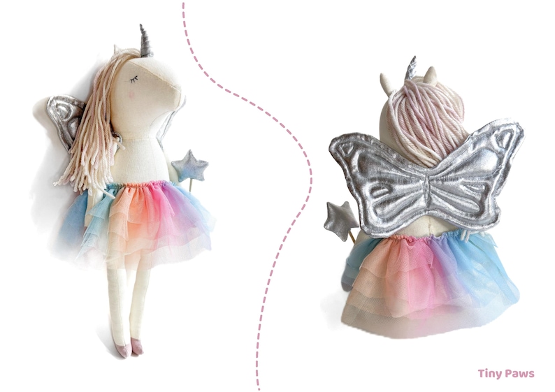 K&ouml;nnte beinhalten: Eine Pl&uuml;sch-Einhorn-Puppe mit silbernem Horn und Fl&uuml;geln sowie einem Regenbogen-Tutu. Die Puppe hat lange, hellfarbene Haare und h&auml;lt einen sternf&ouml;rmigen Zauberstab. Die Fl&uuml;gel sind silberfarben und das Tutu hat einen Farbverlauf.