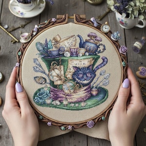 Może przedstawiać: Tamborek do haftu krzyżykowego z fantazyjnym wzorem z Alicji w Krainie Czarów. Projekt zawiera Kota z Cheshire, filiżanki do herbaty i zegarki kieszonkowe, wszystko w zielonym i fioletowym kapeluszu. Drewniany tamborek jest ozdobiony.