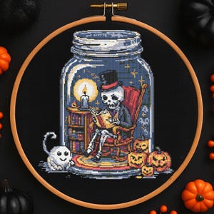 Peut inclure: Une broderie au point de croix sur le thème d'Halloween représentant un squelette en chapeau haut-de-forme lisant à l'intérieur d'un bocal. La scène comprend un fantôme, des citrouilles, une bougie et une bibliothèque, le tout sur fond de ciel étoilé. Le design est encadré dans un cercle à broder en bois.