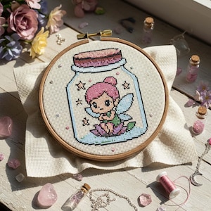 May include: Cross-stitch embroidery in a wooden hoop features a fairy inside a jar. The fairy has pink hair and green wings, sitting on a lotus flower. The jar is surrounded by stars. The background is a light beige fabric.