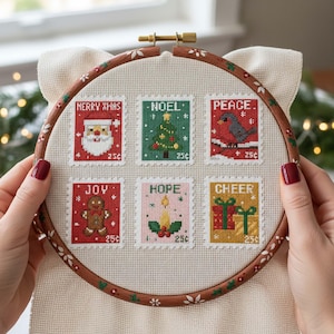 Op de afbeelding: Een borduurring met kruissteek met zes postzegelontwerpen met kerstthema. De postzegels bevatten afbeeldingen van de kerstman, een kerstboom, een vogel, een peperkoekmannetje, een kaars en cadeaus. Elke postzegel heeft de woorden "Merry Xmas", "Noel", "Peace", "Joy", "Hope" en "Cheer".