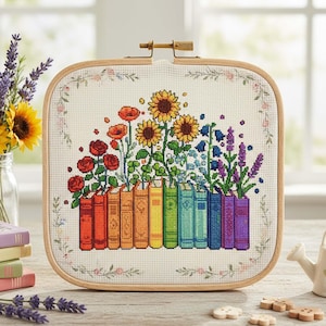 May include: Cross-stitch embroidery featuring a vibrant floral design above a row of books. The flowers include red roses, sunflowers, and lavender. The books are in rainbow colours, set in a square wooden frame.