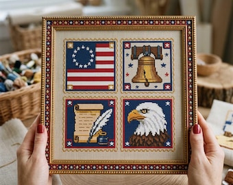 May include: A framed cross-stitch artwork featuring four panels with patriotic symbols. The panels include the American flag, the Liberty Bell, a quill and scroll, and an eagle. The frame is gold with a red and white star border. The artwork is held by a person.
