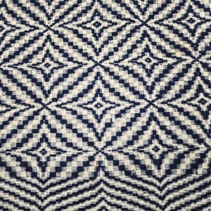May include: A woven textile fabric featuring a repeating geometric pattern of dark navy blue and off-white diamonds. The design consists of small, pixelated squares arranged to form larger star-like shapes across the entire surface of the material.