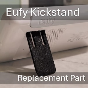 May include: A black replacement kickstand for a white Eufy baby monitor. The kickstand has a textured surface and is designed to be attached to the back of the monitor.