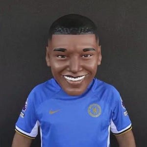 Könnte beinhalten: Eine junge Person trägt ein blaues Fußballtrikot mit goldenem Logo. Das Trikot hat weiße Akzente an den Ärmeln und am Kragen.