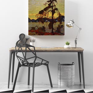 May include: A framed landscape painting depicting a silhouetted tree against a sunset over a lake. The painting hangs above a wooden desk with a black geometric chair, a silver lamp, and a woven basket. The floor has a black and white geometric pattern.