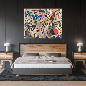May include: A modern bedroom featuring a wooden bed frame with a colourful abstract painting above the headboard. The painting incorporates a range of shapes and colours, including blue, red, yellow, and black. The bed is dressed with white linen and a grey throw pillow. Two wooden bedside tables with lamps are positioned on either side of the bed.