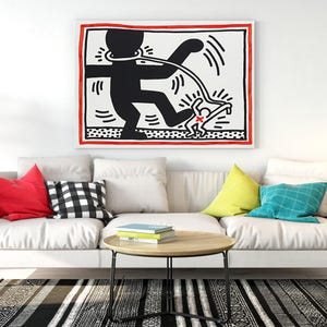 May include: A modern living room featuring a white sofa with colorful pillows, a round wooden coffee table, and a black and white striped rug. A large framed artwork hangs above the sofa, and a black floor lamp stands nearby.