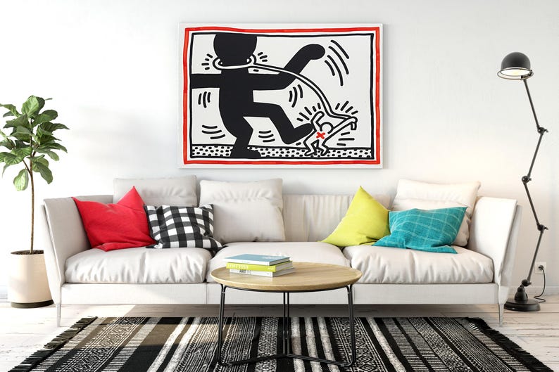 May include: A modern living room featuring a white sofa with colorful pillows, a round wooden coffee table, and a black and white striped rug. A large framed artwork hangs above the sofa, and a black floor lamp stands nearby.