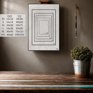 K&ouml;nnte beinhalten: Eine wei&szlig;e Leinwand mit einem schwarzen Rahmen, der verschiedene Gr&ouml;&szlig;en von Drucken mit Ma&szlig;en in Zoll und Zentimetern zeigt. Die Gr&ouml;&szlig;en sind XS, S, M, L, XL und XXL. Die Leinwand befindet sich auf einem Holztisch.