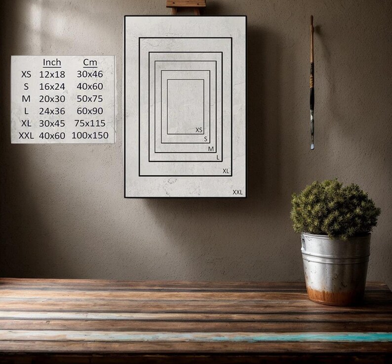 K&ouml;nnte beinhalten: Eine wei&szlig;e Leinwand mit einem schwarzen Rahmen, der verschiedene Gr&ouml;&szlig;en von Drucken mit Ma&szlig;en in Zoll und Zentimetern zeigt. Die Gr&ouml;&szlig;en sind XS, S, M, L, XL und XXL. Die Leinwand befindet sich auf einem Holztisch.